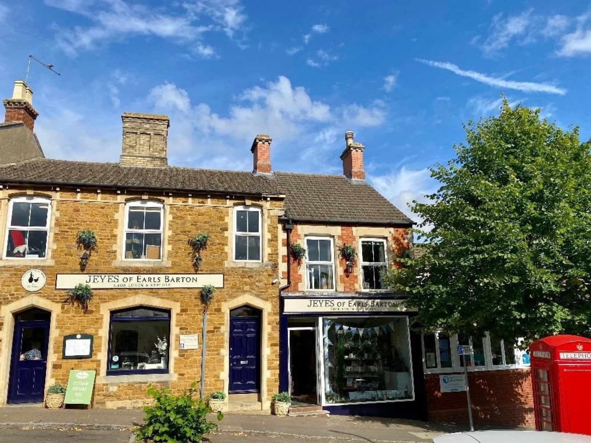 colour photo of the exterior of Jeyes of Earls Barton building, with a green tree and red telephone box to the right